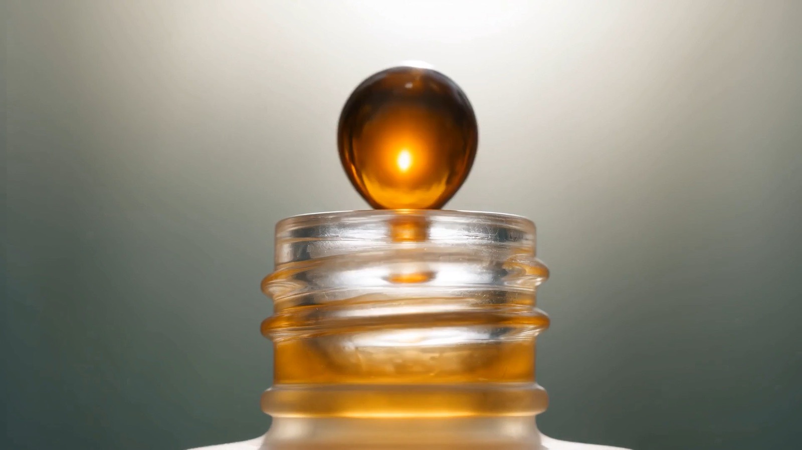 SKÖG film still: a golden drop of serum above an open jar.