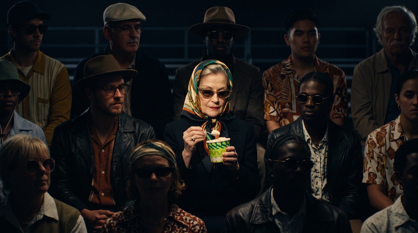 Cast: the woman in the patterned silk headscarf and cat-eye sunglasses.