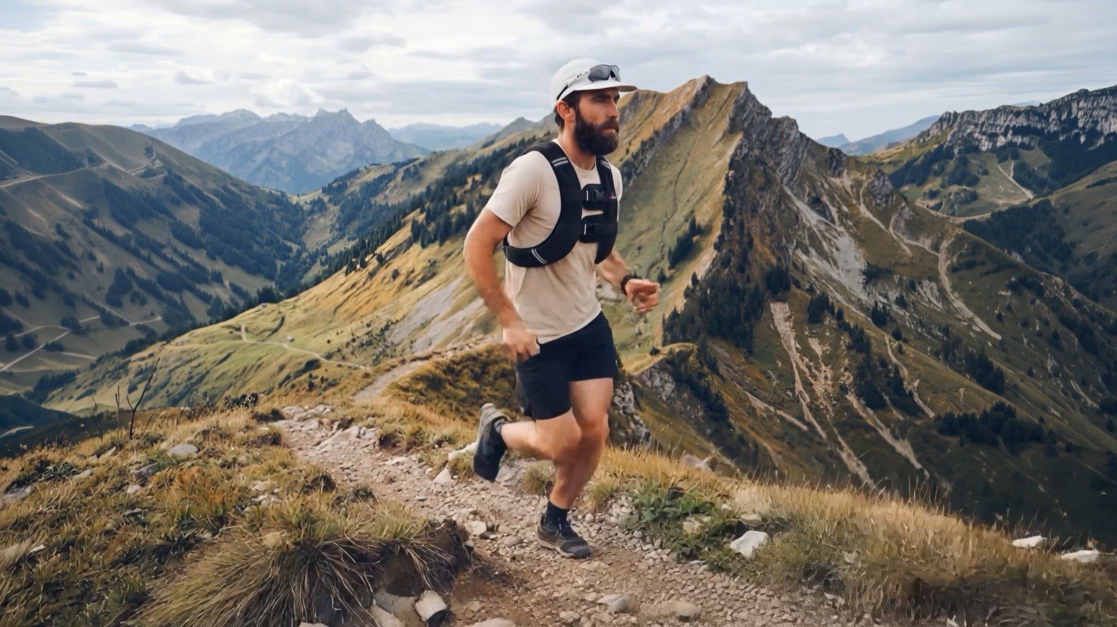 A runner in a black weighted vest on a mountain ridge at golden hour.