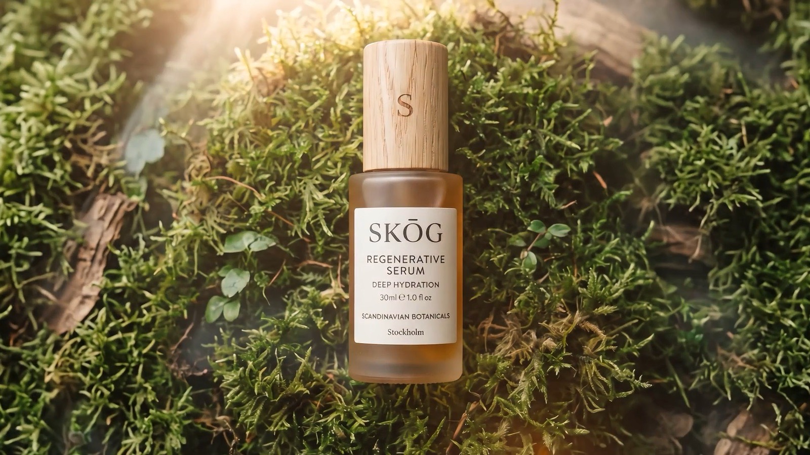 An amber SKÖG serum bottle with an oak cap stands on wet moss in a forest.